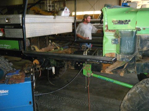 1978 Ford Bronco - Man working on a modified 1978 Ford Bronco in a garage. Toolbox and welding equipment visible.