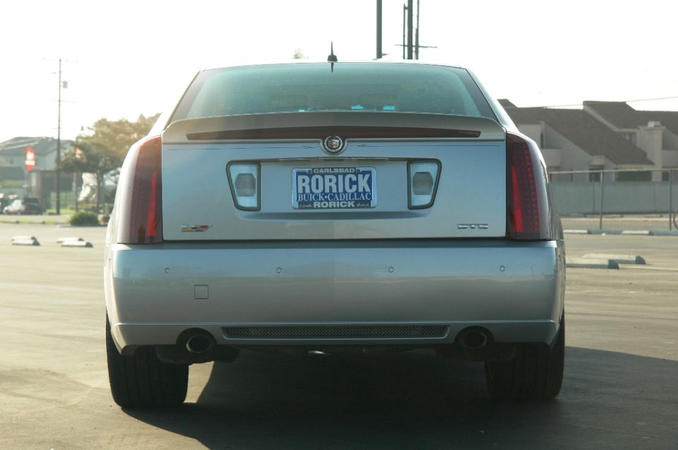 Rear view of a silver Cadillac STS sedan with dual exhaust and dealer plate frame