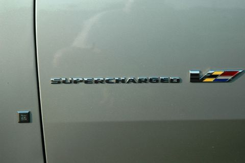 2006 Cadillac STS - Close-up of the "SUPERCHARGED" emblem and V-series badge on a silver vehicle.