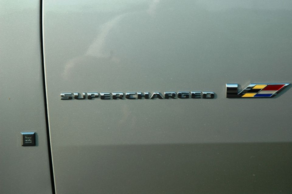 Chrome SUPERCHARGED lettering and Cadillac V-Series badge on a silver-gray fender
