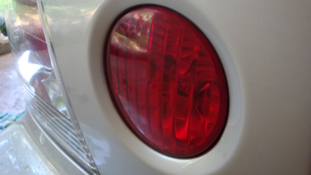 Close-up of round red taillight on a tan car