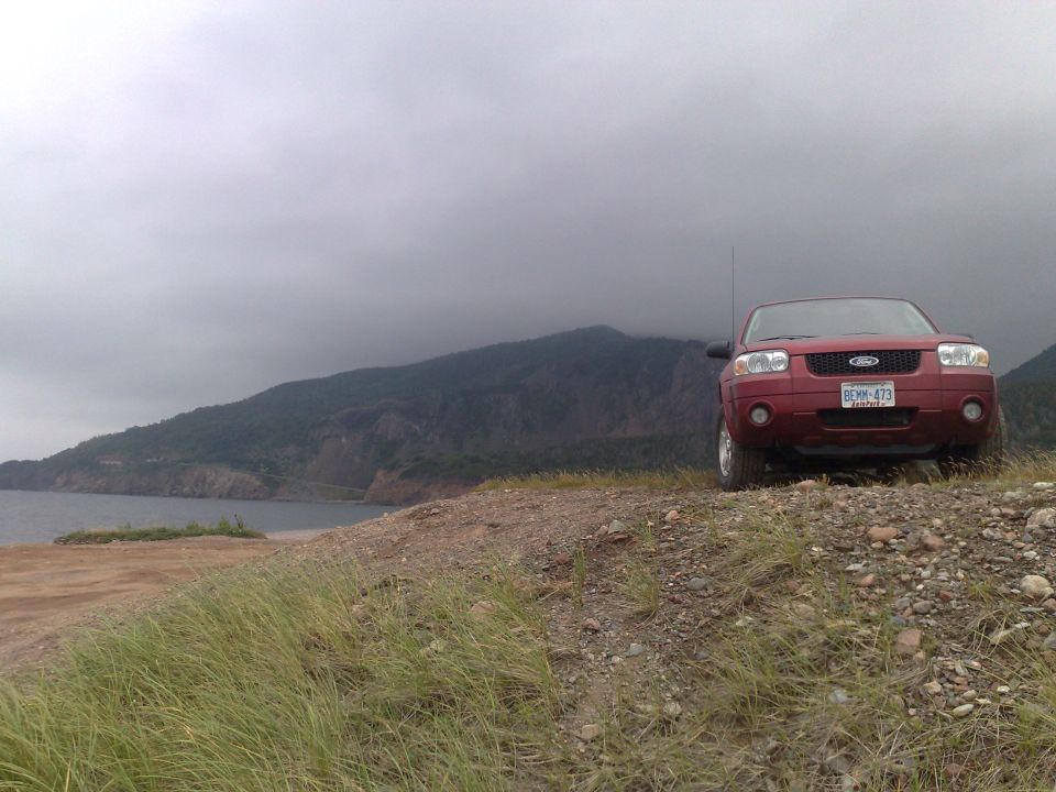 Red SUV parked on a gravelly hill, front view. License plate reads BEXM-473
