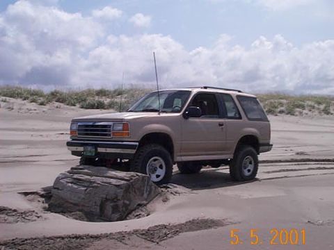 1989 Ford F-150 - A 1991 Ford Explorer navigates a sandy terrain with its front tire resting on a large rock.