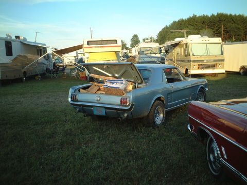 1967 Ford Galaxie - A blue 1966 Ford Mustang coupe is parked in a grassy field with its trunk open, loaded with supplies.