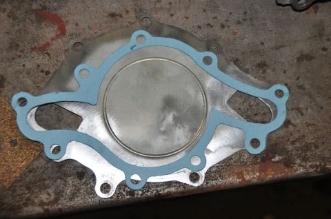 1996 Ford Bronco - A water pump gasket with blue sealant is shown on a metal surface, likely for engine repair.