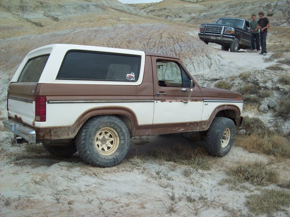 Brown and white Ford Bronco in off-road terrain