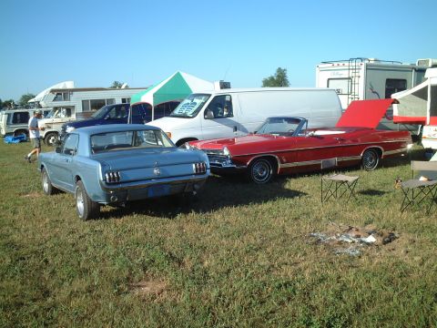 1967 Ford Galaxie - A blue 1965 Ford Mustang is parked at an outdoor event with other vehicles and RVs.
