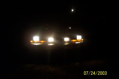 1991 Ford Crown Victoria LTD - The front of a car is visible at night, with its headlights and turn signals on.