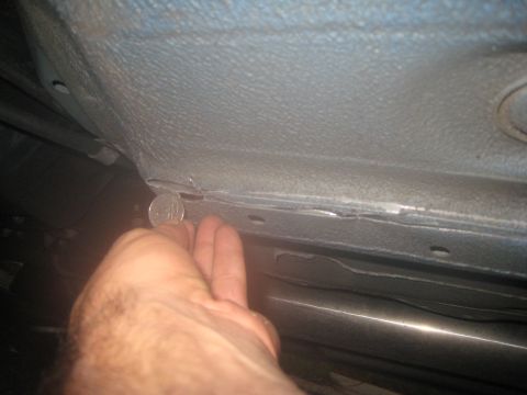 2007 Subaru Impreza - A coin is used to show the scale of damage on the underside of a vehicle.
