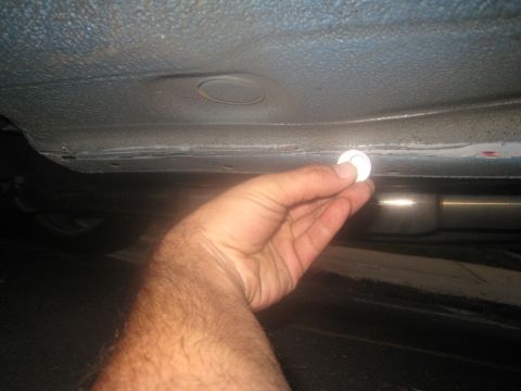 2007 Subaru Impreza - Close-up of a hand holding a coin near the undercarriage of a vehicle.