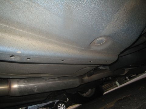 2007 Subaru Impreza - The underside of a vehicle is shown, with the exhaust pipe and a wheel visible, along with another car in the background.