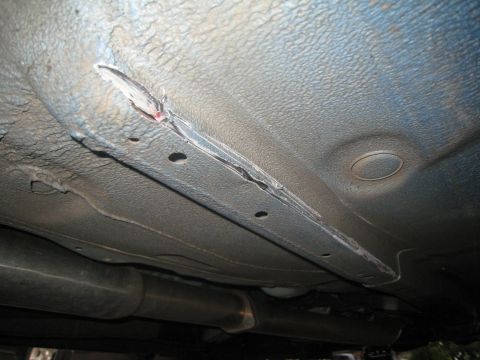 2007 Subaru Impreza - Close-up view of the underbody showing damage to the frame rail and rust.