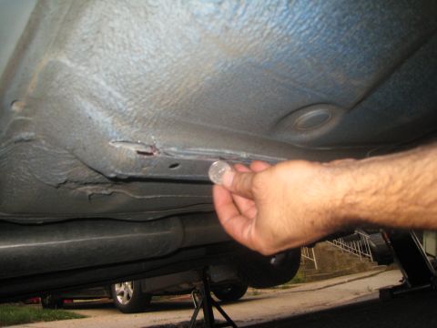 2007 Subaru Impreza - A coin is used to show the size of a hole in the vehicle's undercarriage.