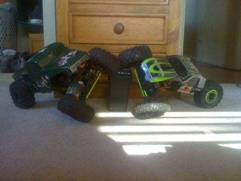 1995 Ford Bronco - Two remote-controlled rock crawler trucks are shown on a carpeted floor in front of a wooden dresser.