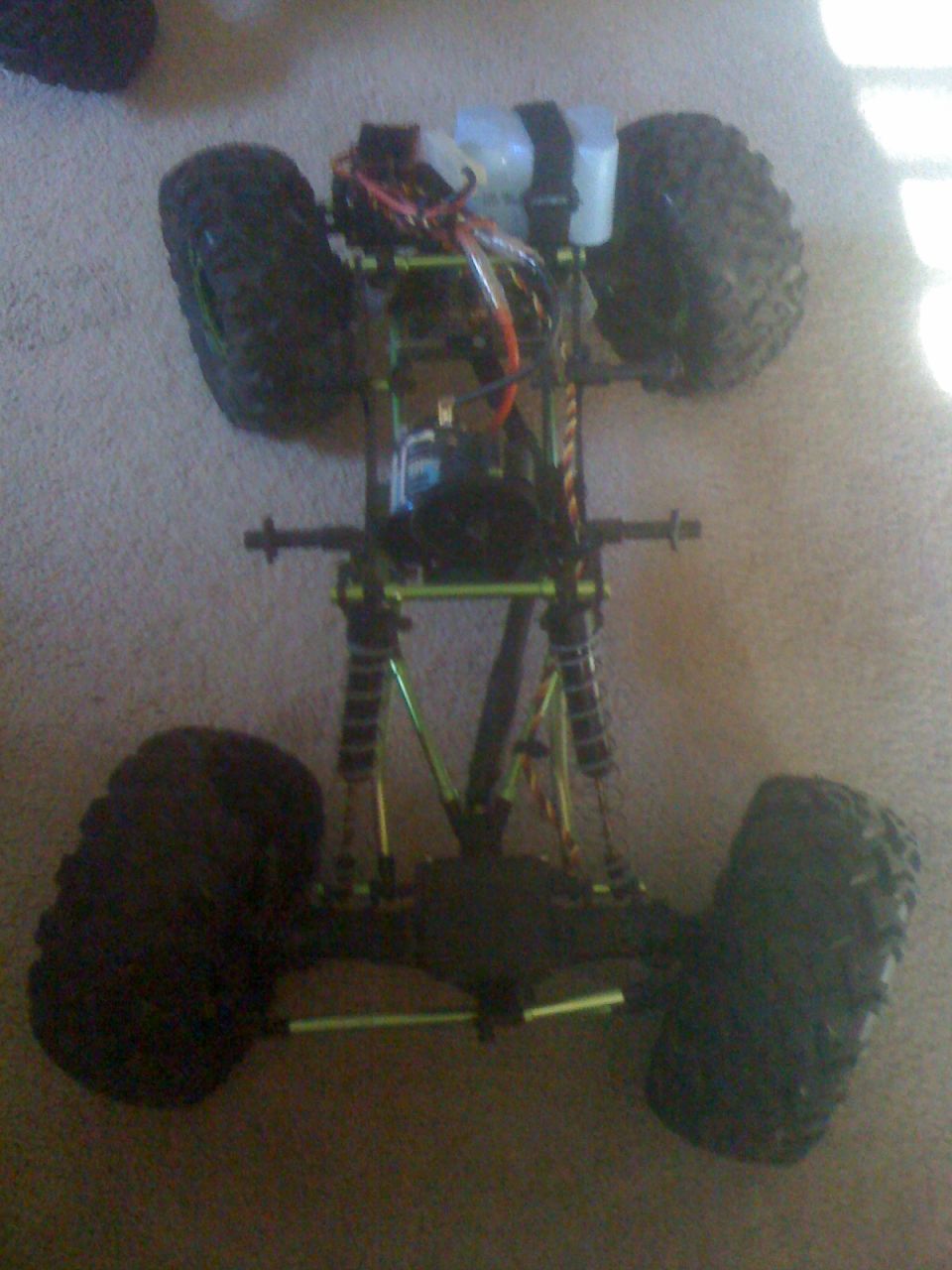 RC rock crawler chassis with large tires, shocks, and electronics visible