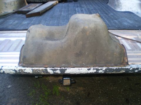 1979 Ford Bronco - This is an oil pan, likely removed from a vehicle, resting on a truck bed liner.