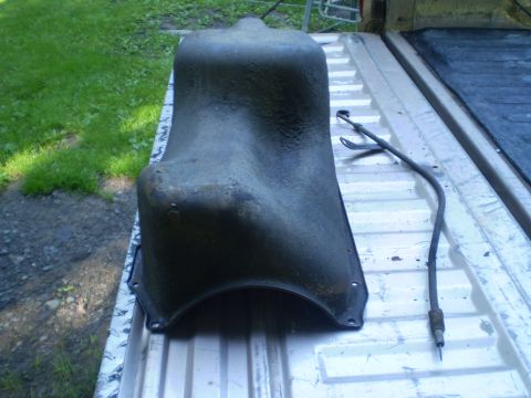 1979 Ford Bronco - Oil pan and dipstick are shown resting on the bed of a pickup truck, with grass and dirt visible in the background.