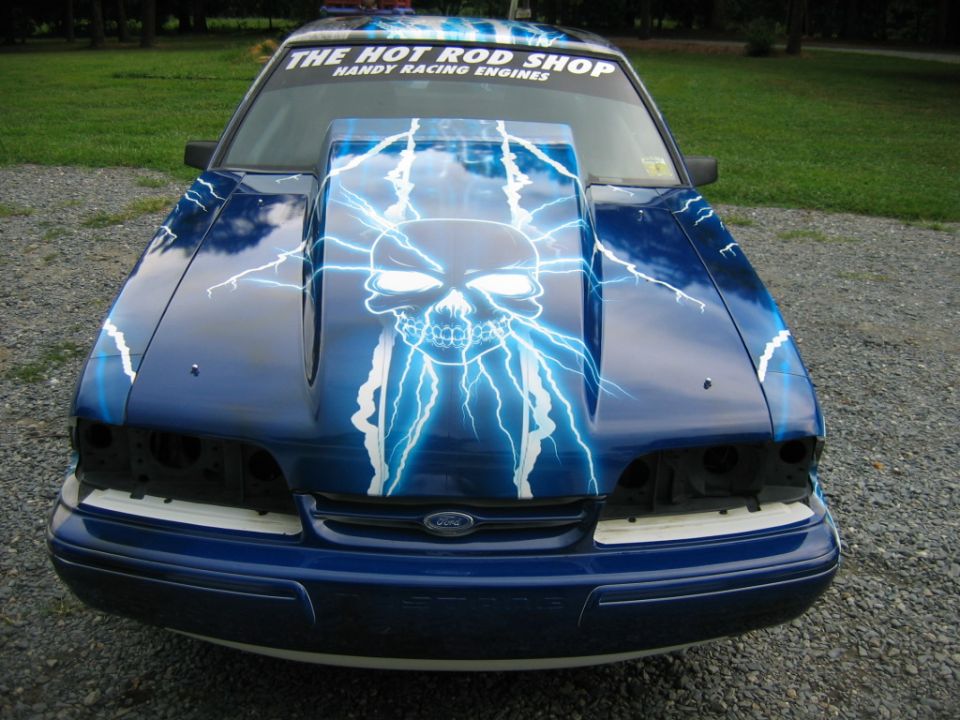1992 Ford Mustang front end with custom skull and lightning bolt paint, "THE HOT ROD SHOP" sticker on windshield
