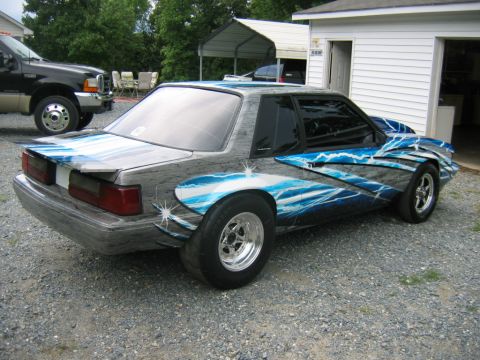 1992 Ford Mustang - Customized 1992 Ford Mustang coupe with a striking lightning bolt paint scheme, viewed from the rear three-quarter angle.