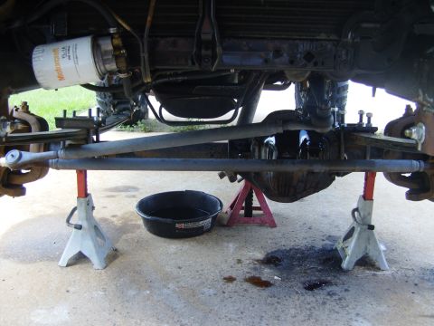 1995 Ford Bronco - The vehicle's undercarriage is supported by jack stands, revealing the steering components and a freshly changed oil filter.