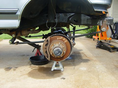 1995 Ford Bronco - Undercarriage of a vehicle undergoing suspension work, with components exposed and supported by jack stands.