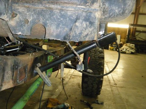 1978 Ford Bronco - This image shows modifications being made to the frame and suspension of a vehicle, with a large tire visible.