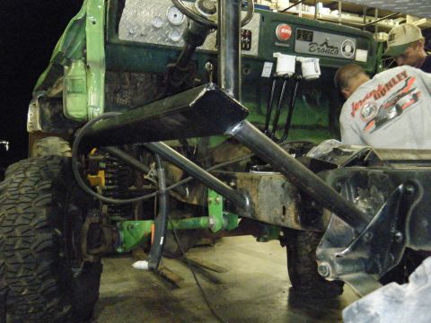 1978 Ford Bronco - The interior of a green 1978 Ford Bronco shows modifications including a roll cage and diamond plate dashboard as two individuals work on t…