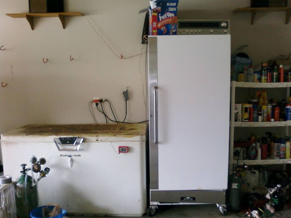 Chest freezer with a digital thermometer and an upright refrigerator in a garage