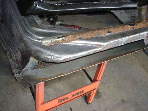 1979 Ford F-250 - A heavily rusted metal panel, likely from a vehicle's body, is supported by orange sawhorses in a workshop.