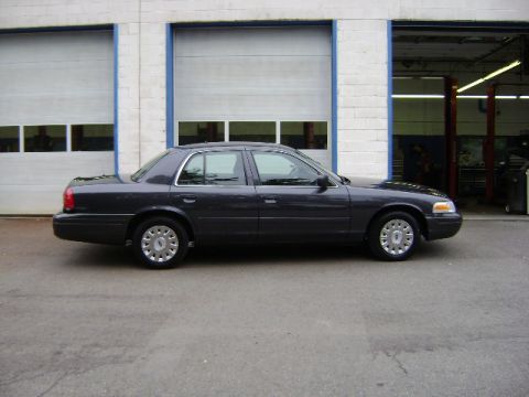 2001 Ford Crown Victoria - Side view of a dark gray 2001 Ford Crown Victoria sedan parked outside a commercial building.