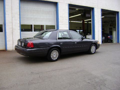 2001 Ford Crown Victoria - A dark gray 2001 Ford Crown Victoria is parked outside a commercial garage.