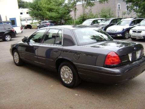 2001 Ford Crown Victoria - A dark gray 2001 Ford Crown Victoria sedan is parked in a lot with other vehicles.