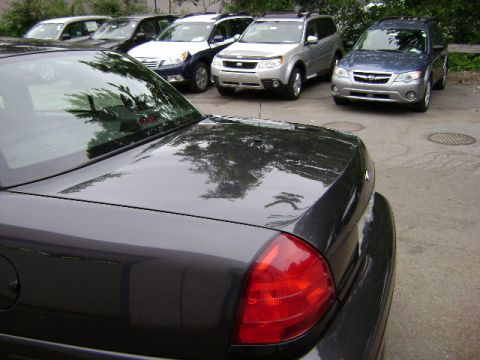 2001 Ford Crown Victoria - Rear view of a dark gray 2001 Ford Crown Victoria, parked in a lot with several other vehicles visible.