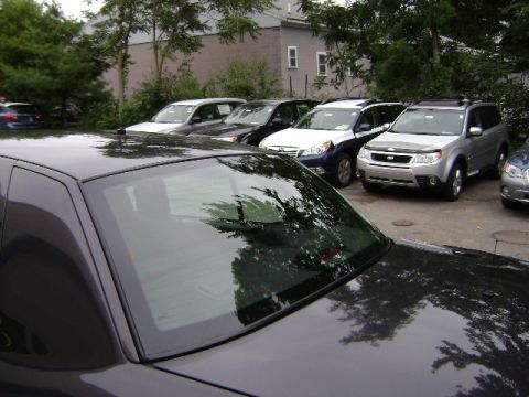 2001 Ford Crown Victoria - A variety of vehicles are parked in an outdoor lot, with trees and buildings in the background.