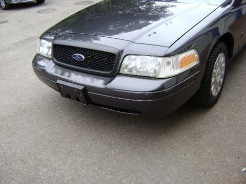 2001 Ford Crown Victoria - A dark gray Ford Crown Victoria is shown from the front, with its grille and headlights visible.
