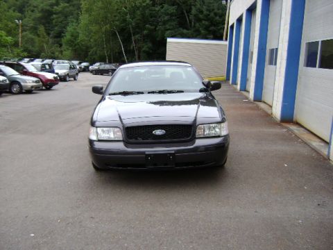 2001 Ford Crown Victoria - A 2001 Ford Crown Victoria is parked in front of a commercial building with multiple garage bays.