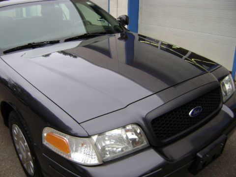 2001 Ford Crown Victoria - A dark gray Ford Crown Victoria is shown from the front, highlighting its grille and a police spotlight.