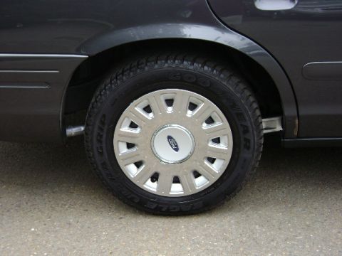 2001 Ford Crown Victoria - Rear wheel and fender of a 2001 Ford Crown Victoria, showing the hubcap and tire detail.