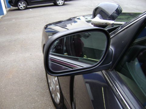 2001 Ford Crown Victoria - A dark police car is parked next to another vehicle, with a spotlight visible above the side mirror.