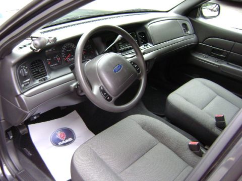 2001 Ford Crown Victoria - The interior of a 2001 Ford Crown Victoria is shown, a dashboard, steering wheel, and front seats with a Saab branded floor mat.