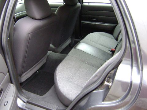 2001 Ford Crown Victoria - The rear interior of a vehicle shows fabric seats and black carpeting on the floor.