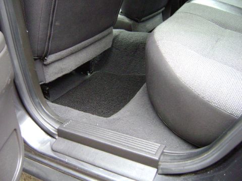 2001 Ford Crown Victoria - The interior view shows the rear passenger footwell and seats, black carpeting and floor mats.