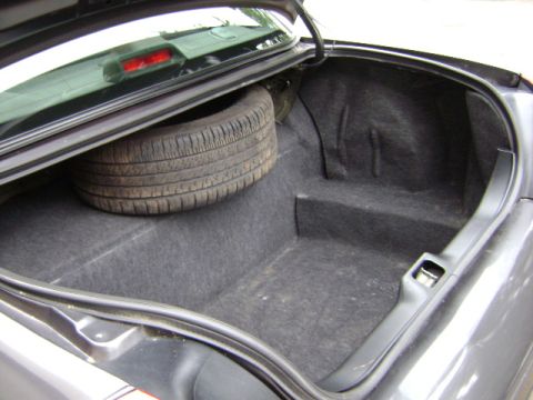 2001 Ford Crown Victoria - The trunk of a car is open, revealing a spare tire and the carpeted storage area.