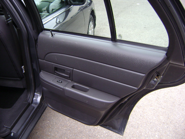 Close-up of a car's rear passenger door panel and interior. Another car is visible through the window