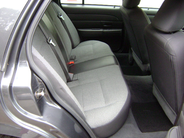 Back seat and door panel of a dark gray sedan. Gray fabric seats with black accents and seatbelts