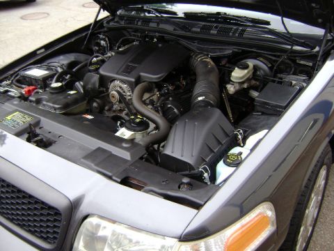 2001 Ford Crown Victoria - The engine bay of a dark gray Ford Crown Victoria is visible with the hood open.