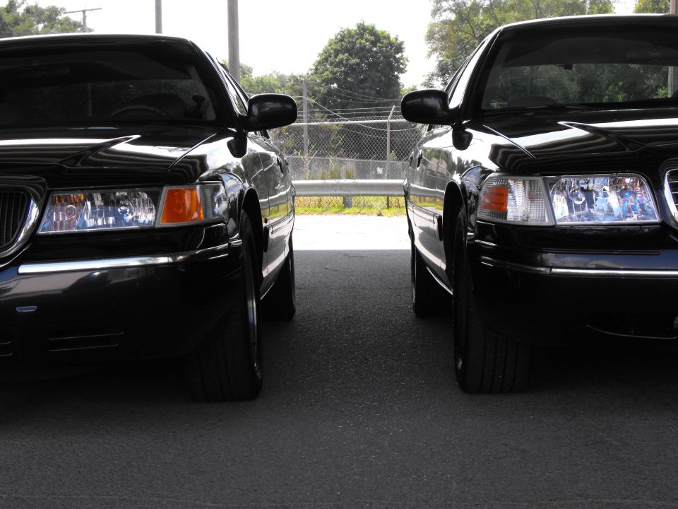 Two black 1998 Ford Crown Victorias parked side-by-side, front view