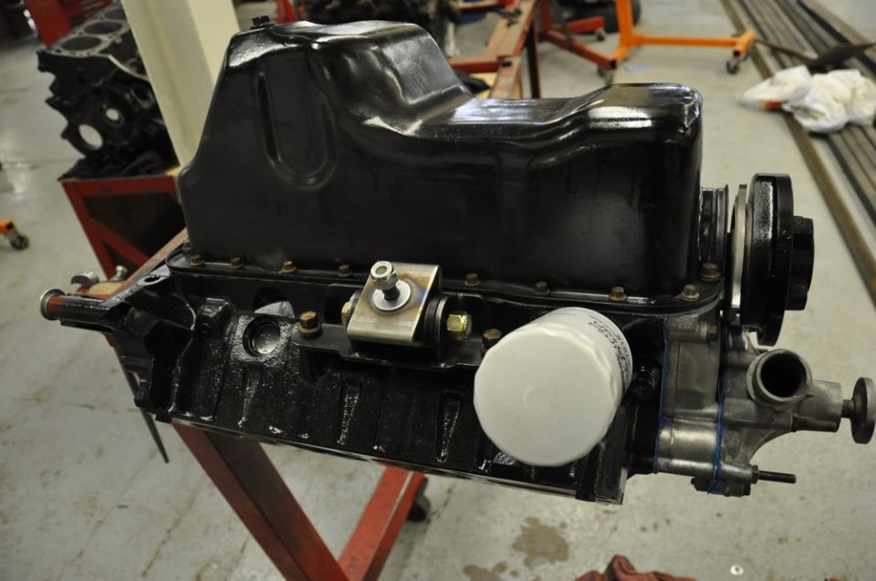 Engine block with black oil pan, white oil filter, and pulley assembly mounted