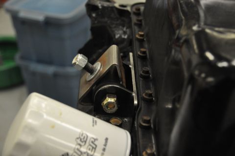 1996 Ford Bronco - A white oil filter is positioned near a custom metal bracket attached to an engine block.