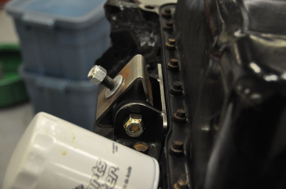 Close-up of an engine oil filter next to a metal bracket with bolts